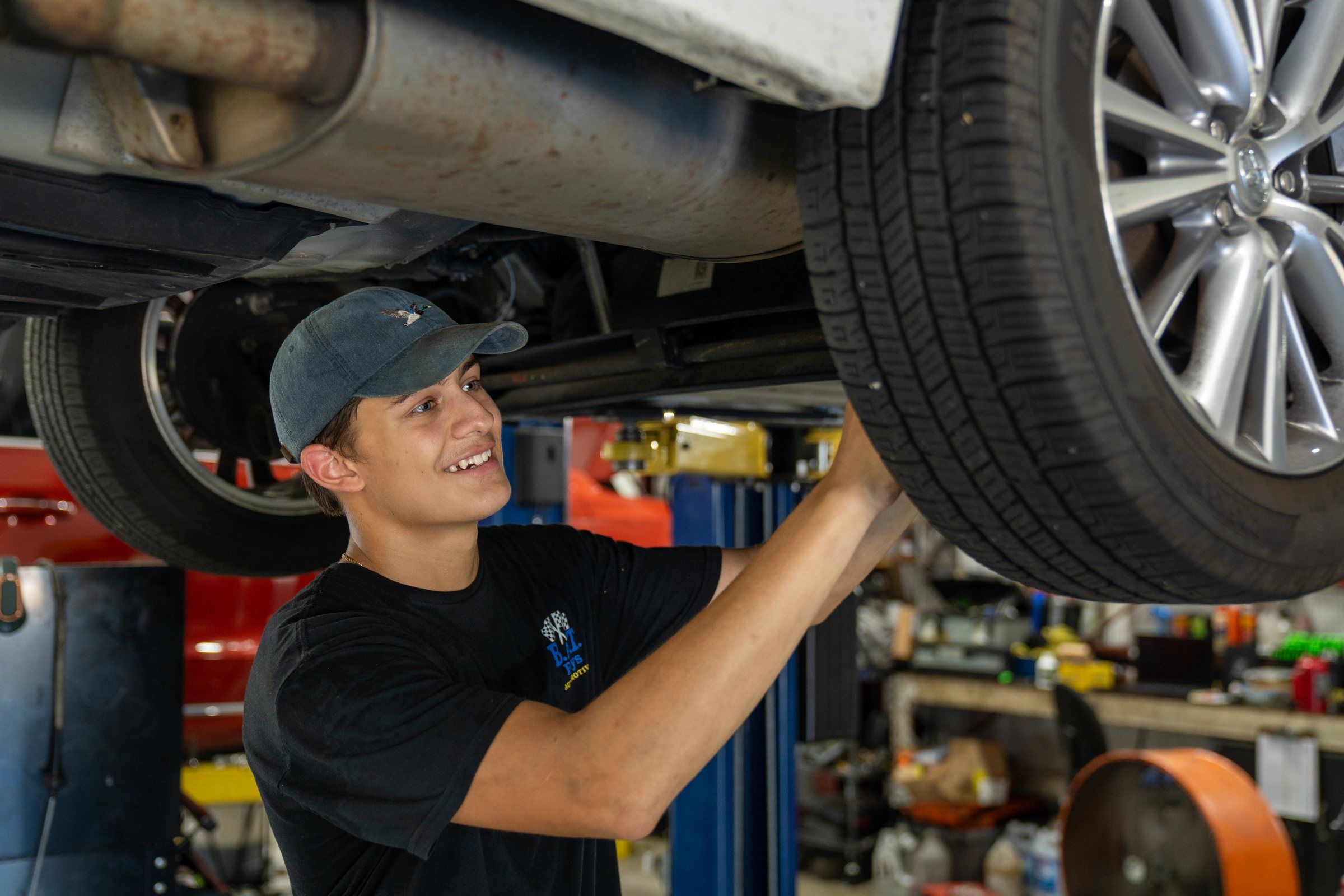 A Future Men apprentice working under a car at a local auto shop