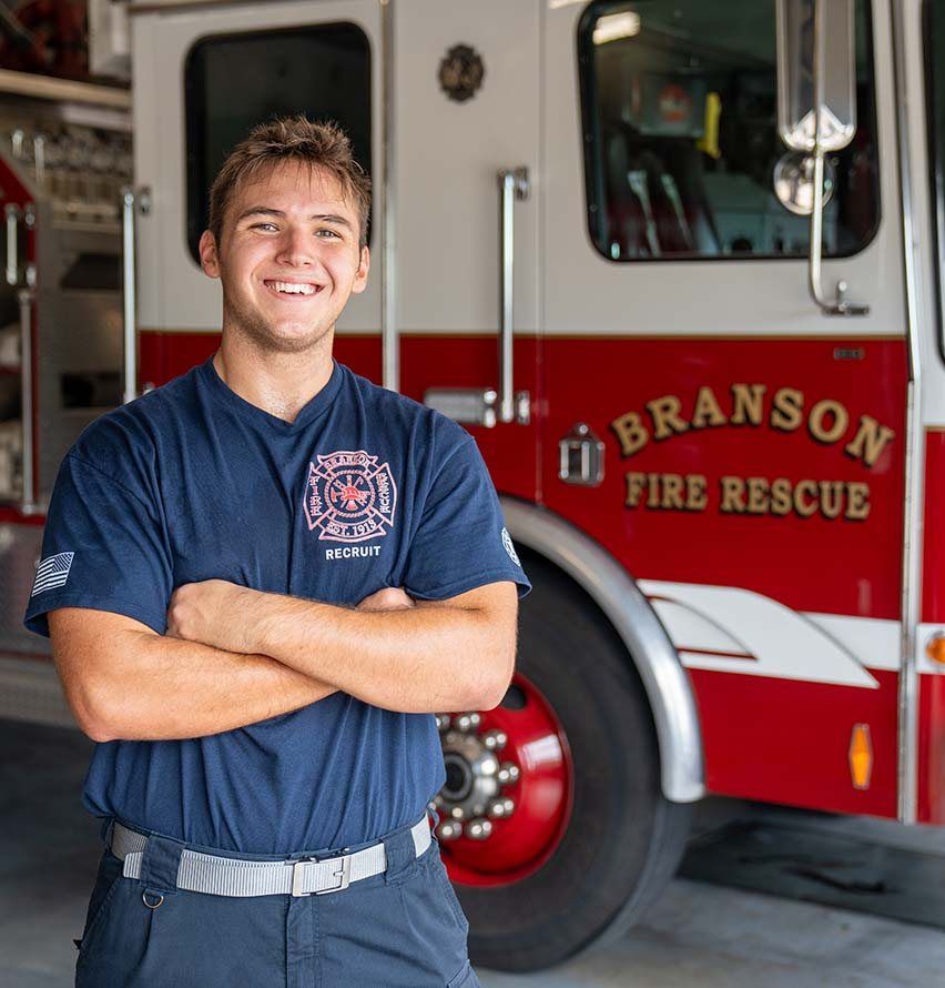 A Future Men student in uniform at his apprenticeship with Branson Fire Rescue, standing in front of a fire engine