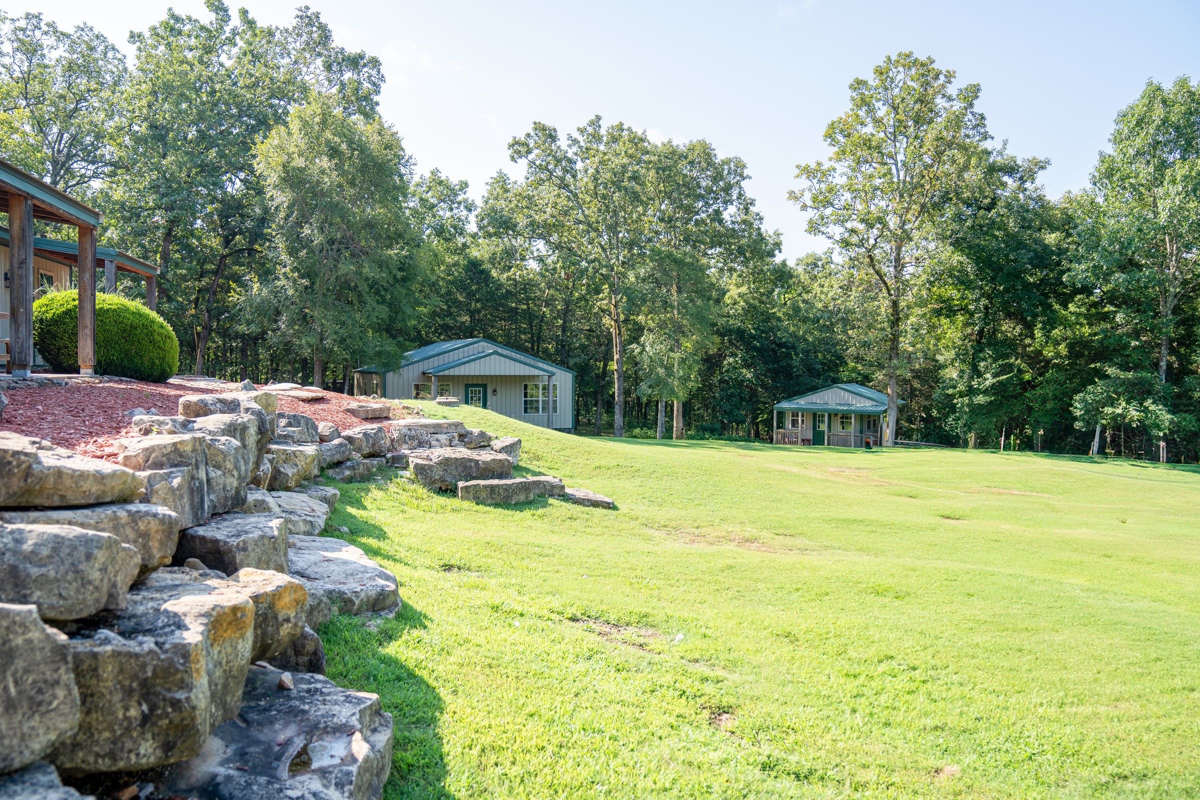 The rock garden and lawn on the Future Men campus, with cabins among the trees