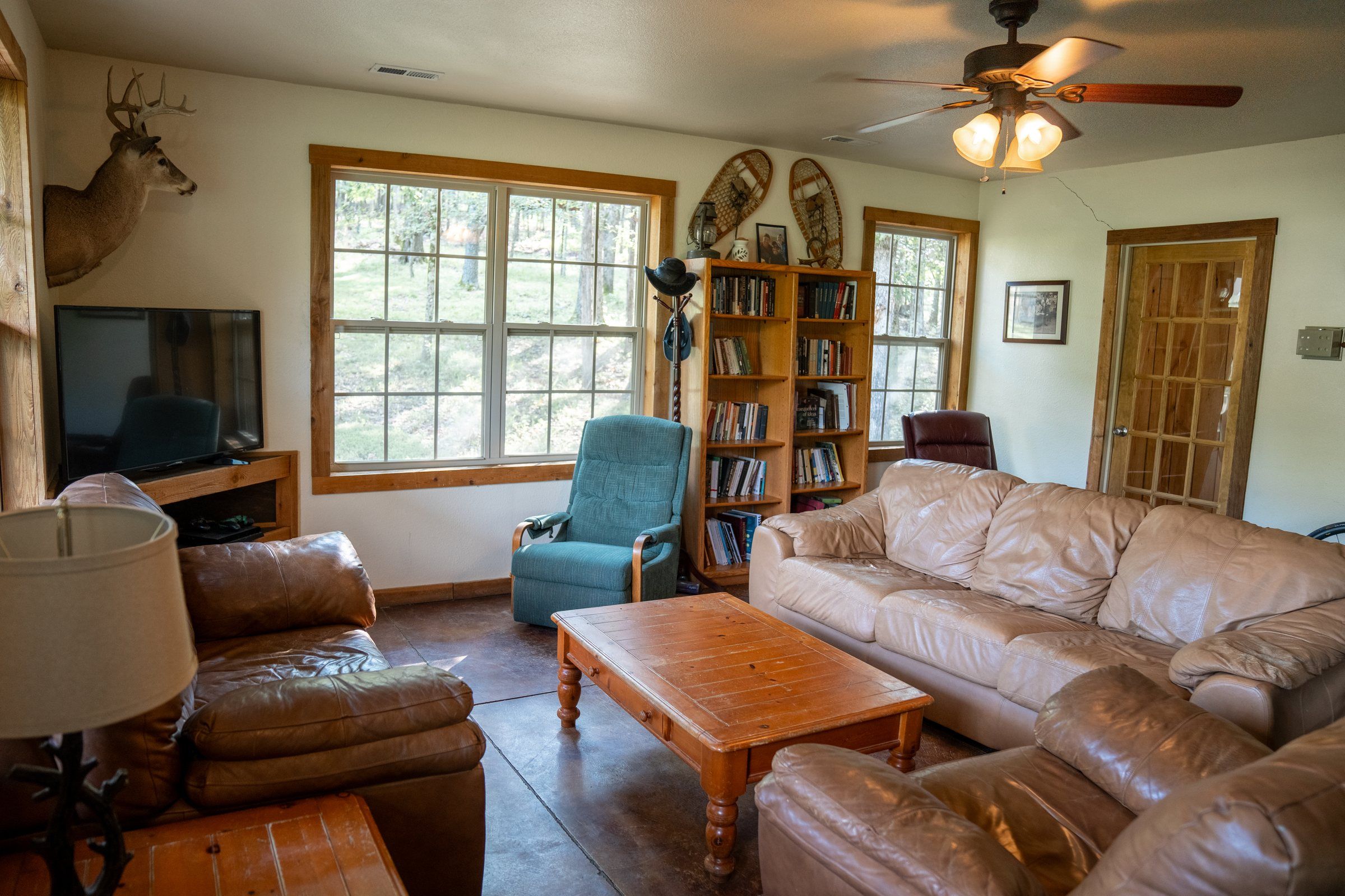 The lodge living room at Future Men, with leather couches, bookshelves and a mounted deer head