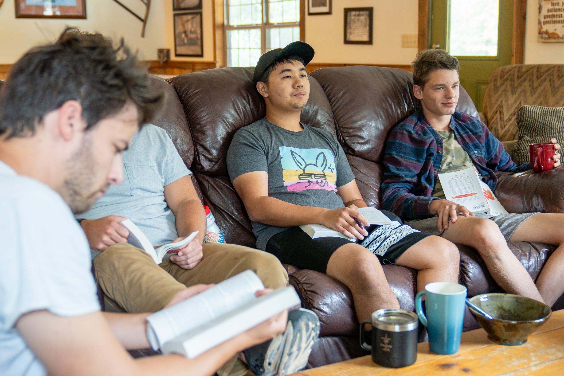 Future Men students reading together on leather couches in the lodge