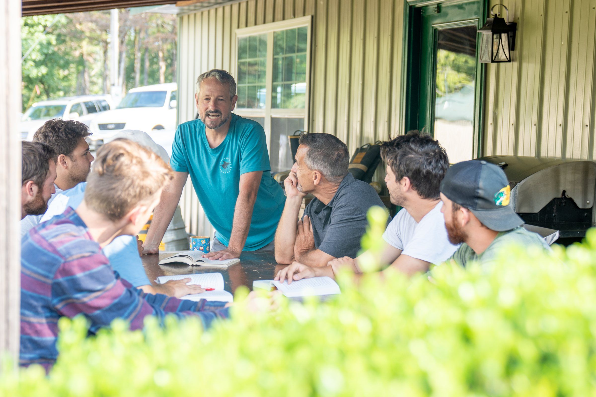 A Future Men mentor leading a Bible study with students around the porch table