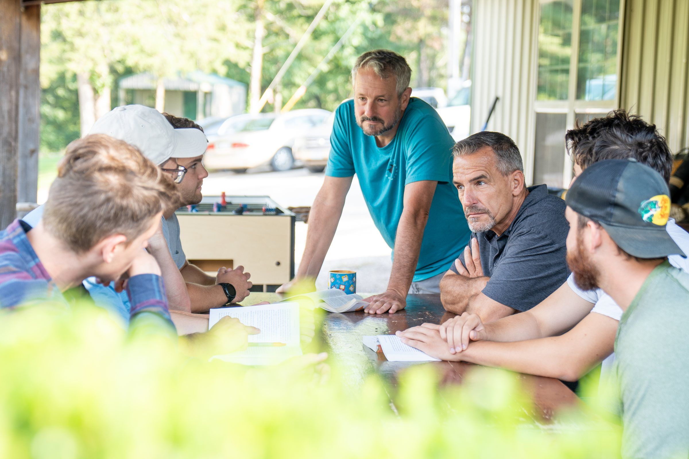 Future Men mentors and students talking around a table on the porch