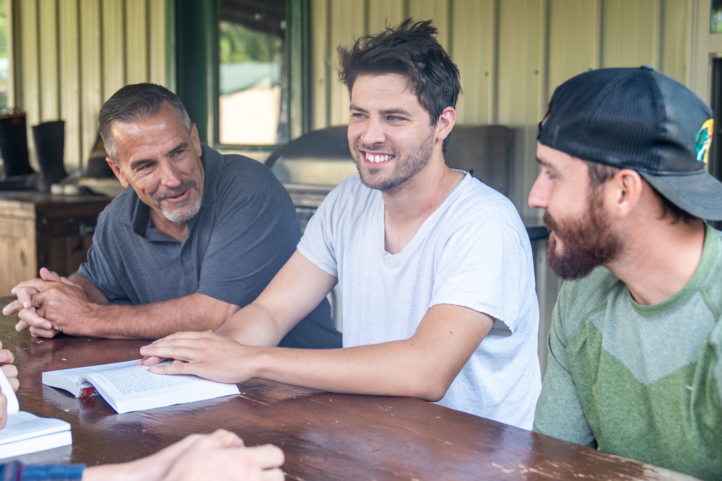 Future Men mentors and students laughing together around a table with open Bibles