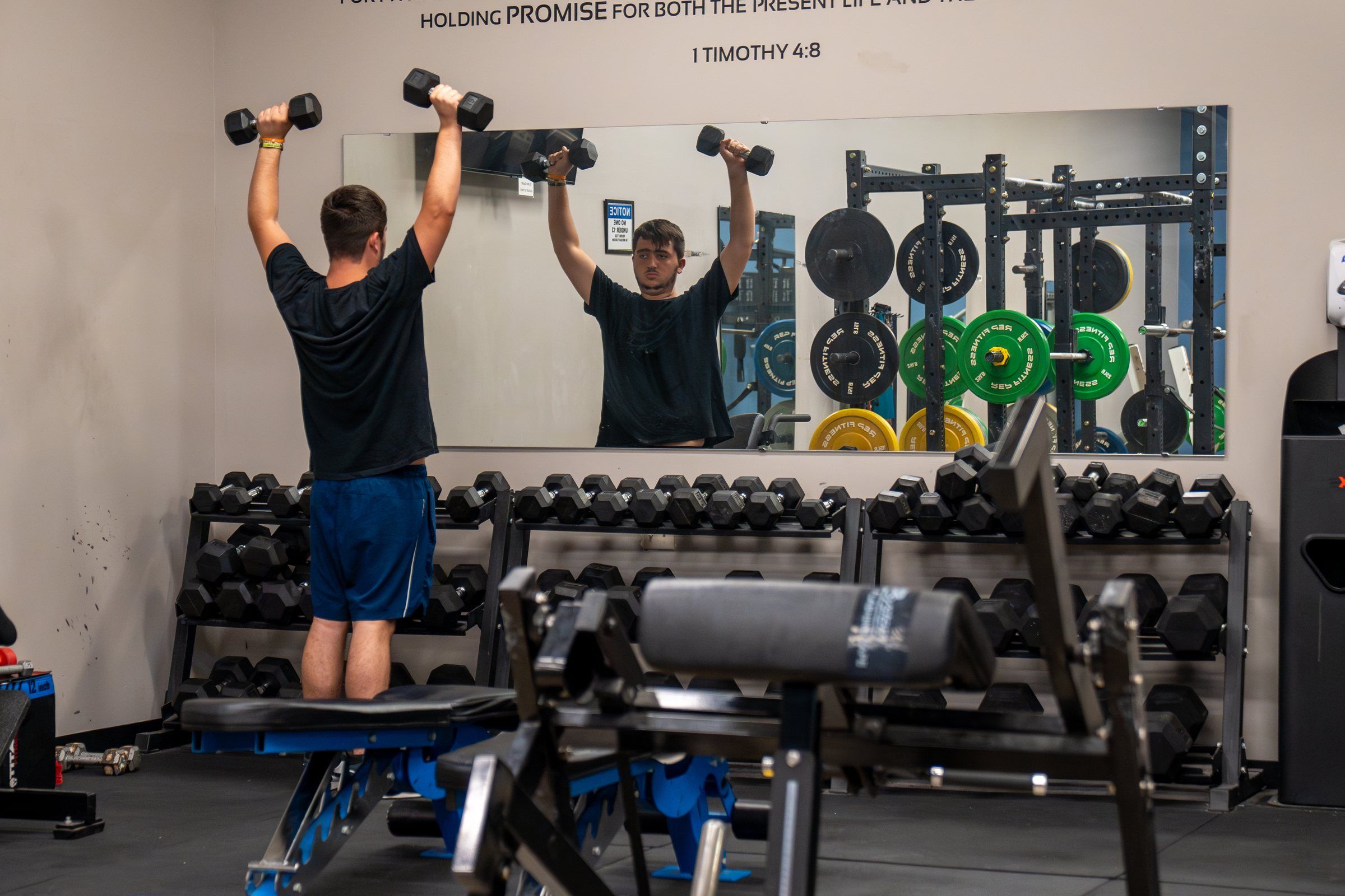 A student lifting dumbbells in the Future Men weight room