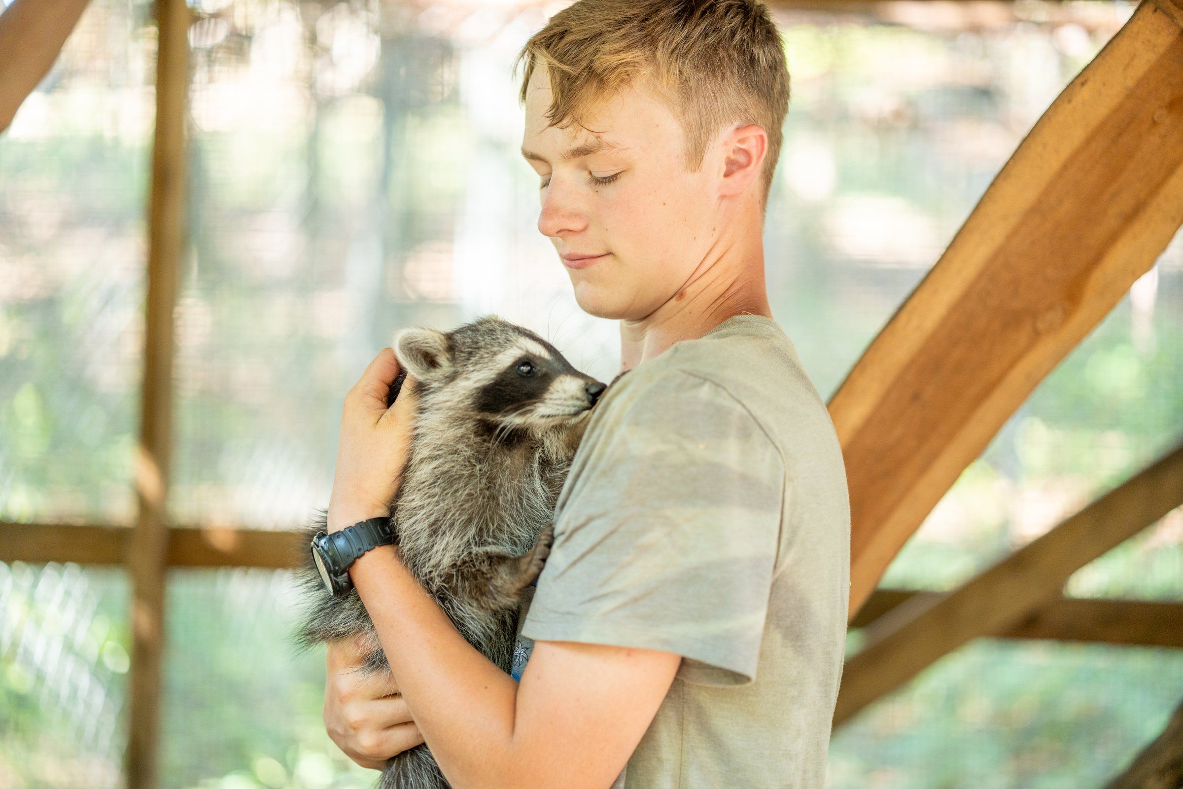 A Future Men student holding a rehabilitated raccoon in the wildlife enclosure