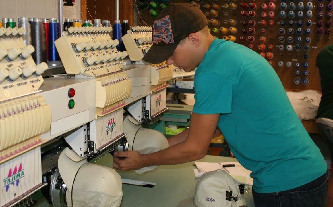 A Future Men apprentice running an embroidery machine at a local shop