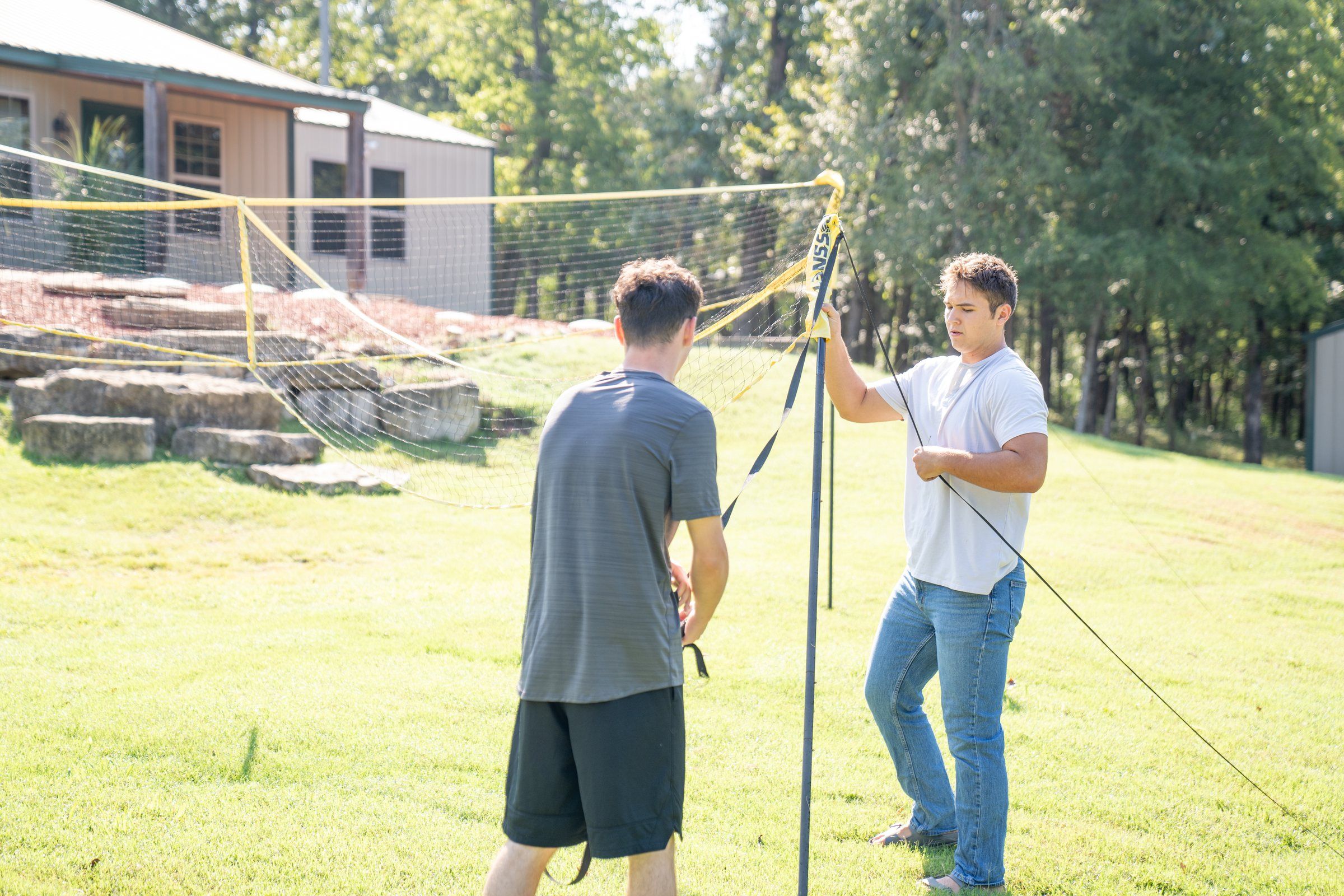 Two Future Men students setting up a net on the campus lawn