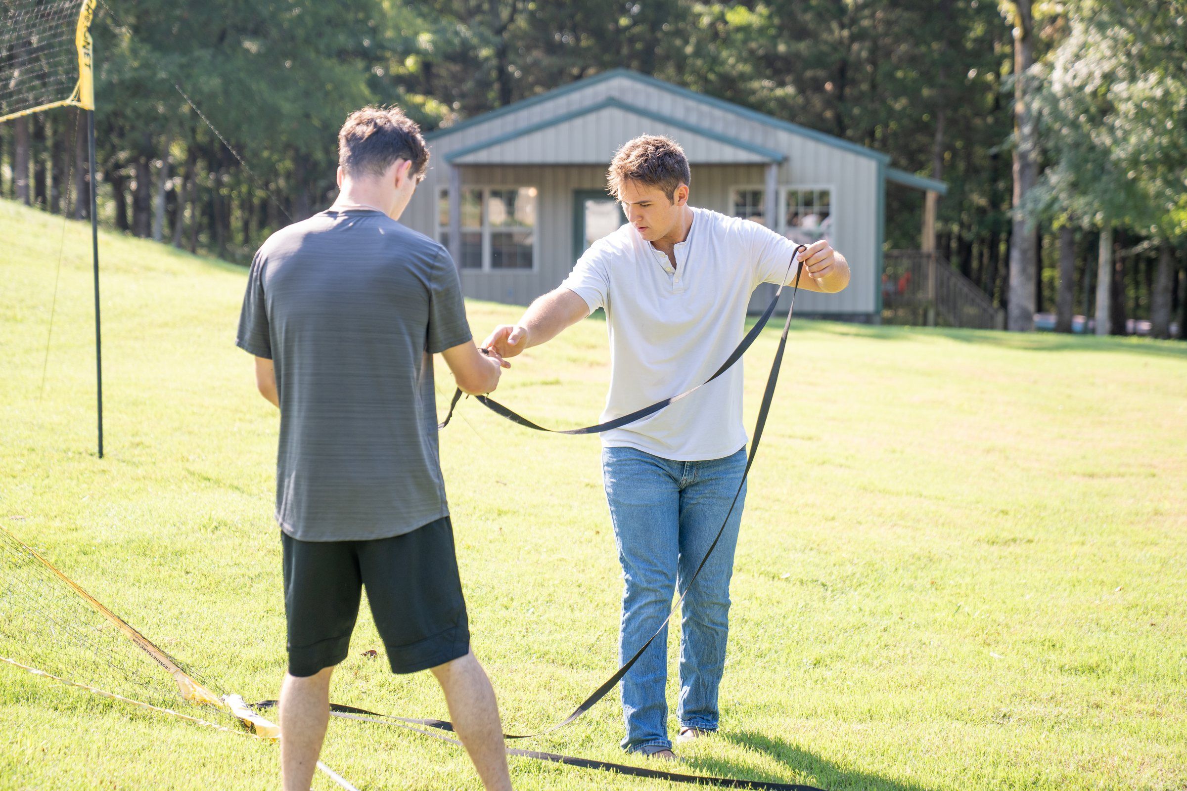 Two Future Men students setting up a volleyball net on the campus lawn